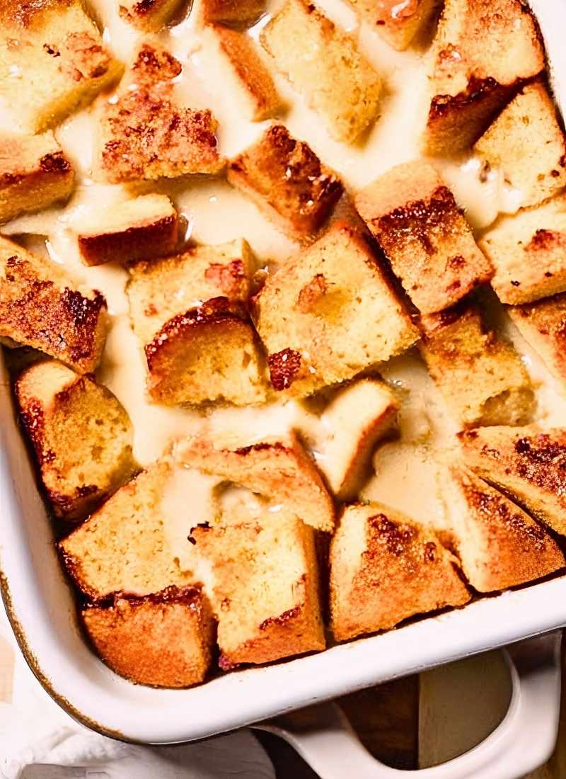 A baking dish fresh out of the oven with sourdough French toast casserole featuring perfectly baked slightly crispy bread pieces with visible layers No excessive shine just a warm delicious t