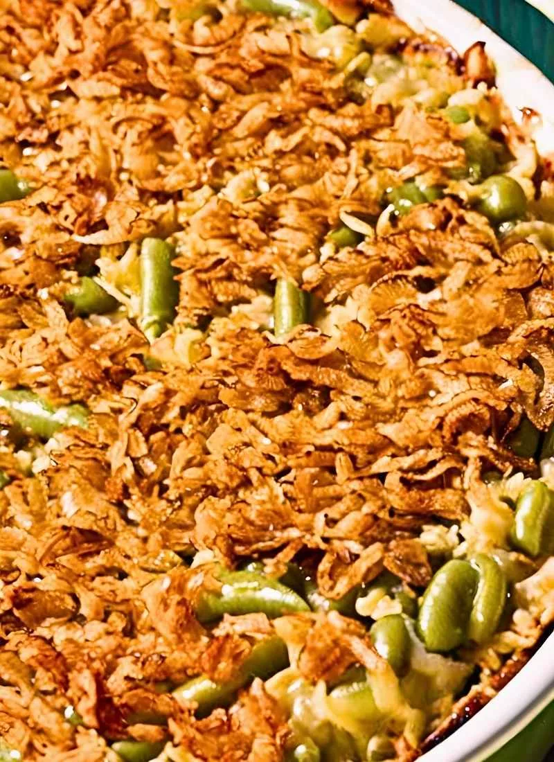 A close up shot of Campbell’s Green Bean Casserole, highlighting the crispy, golden brown fried onion topping. The onions are lightly crisped with a golden hue, while the creamy green bean mixture