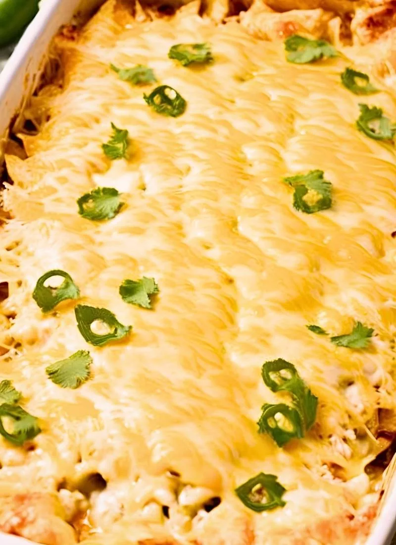 A close-up shot of a freshly baked Green Chili Chicken Enchilada Casserole, capturing the bubbling, golden-brown melted cheese on top. The surface has crispy edges with gooey, stretchy cheese laye