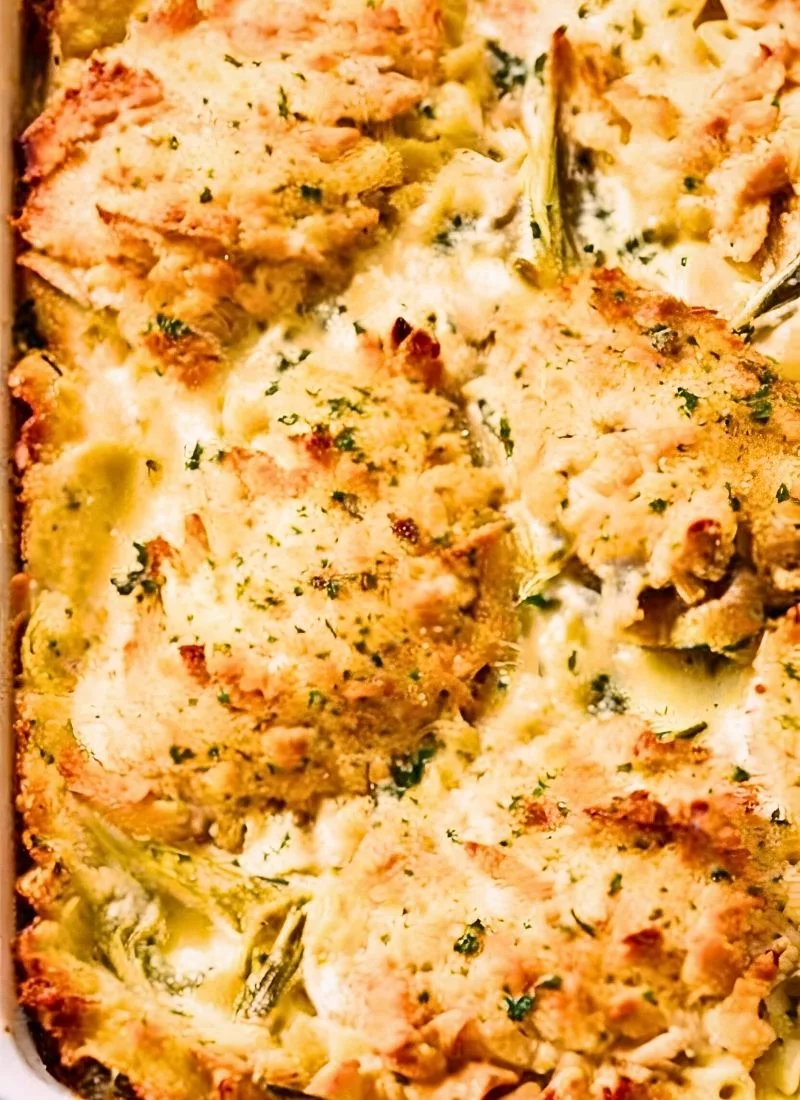 A fork lifting a cheesy bite from the Spaghetti Casserole Baked with strings of melted cheese stretching between the layers The rich red sauce clings to the spaghetti making it look hearty ()