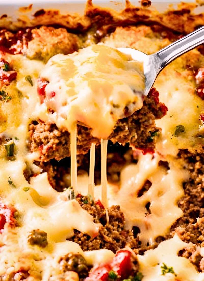 A spoon lifting a portion of meatloaf casserole revealing the moist savory meat layer topped with smooth mashed potatoes and gooey melted cheese Natural texture no overexposed lighting