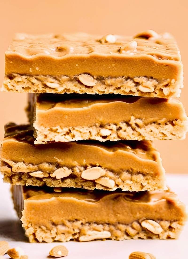 A stack of oatmeal peanut butter bars with one slightly tilted to reveal the dense oat packed interior and creamy peanut butter layer No overexposed lighting just a natural homemade look