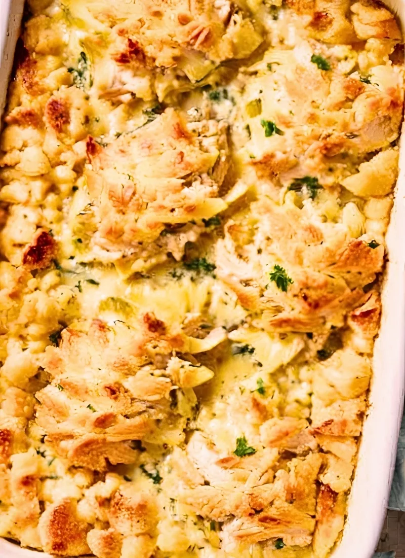 Close up of Chicken Artichoke Casserole fresh out of the oven – The cheese is bubbling with crispy golden edges and a creamy rich filling peeking through