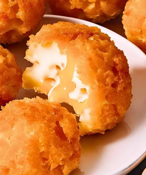 Close up of crispy golden brown Cheese Balls stacked on a plate – The perfectly round crunchy exterior glistens lightly with a few cracked open revealing gooey melted cheese inside ()
